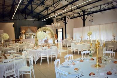 Salle avec des rangées de chaises en plastique beige face à une scène surélevée dans un espace lumineux.