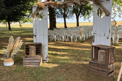 Salle avec des rangées de chaises en plastique beige face à une scène surélevée dans un espace lumineux.