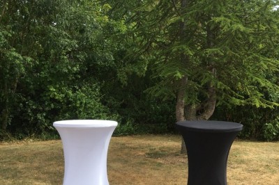 Salle avec des rangées de chaises en plastique beige face à une scène surélevée dans un espace lumineux.