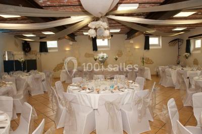 Salle avec des rangées de chaises en plastique beige face à une scène surélevée dans un espace lumineux.
