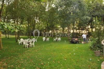 Salle avec des rangées de chaises en plastique beige face à une scène surélevée dans un espace lumineux.