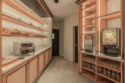 Chambre d'hôtel lumineuse avec lit double, bureau, fauteuil, grandes fenêtres et vue sur un balcon.