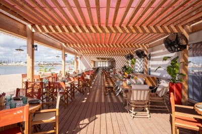 Chambre d'hôtel lumineuse avec lit double, bureau, fauteuil, grandes fenêtres et vue sur un balcon.