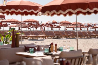 Chambre d'hôtel lumineuse avec lit double, bureau, fauteuil, grandes fenêtres et vue sur un balcon.
