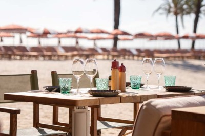Chambre d'hôtel lumineuse avec lit double, bureau, fauteuil, grandes fenêtres et vue sur un balcon.
