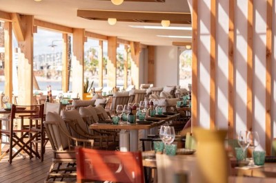 Chambre d'hôtel lumineuse avec lit double, bureau, fauteuil, grandes fenêtres et vue sur un balcon.
