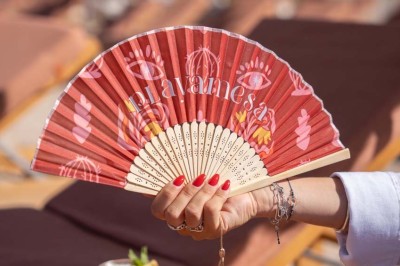 Chambre d'hôtel lumineuse avec lit double, bureau, fauteuil, grandes fenêtres et vue sur un balcon.