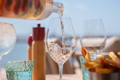 Chambre d'hôtel lumineuse avec lit double, bureau, fauteuil, grandes fenêtres et vue sur un balcon.