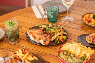 Chambre d'hôtel lumineuse avec lit double, bureau, fauteuil, grandes fenêtres et vue sur un balcon.