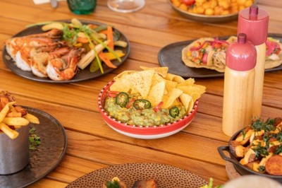 Chambre d'hôtel lumineuse avec lit double, bureau, fauteuil, grandes fenêtres et vue sur un balcon.