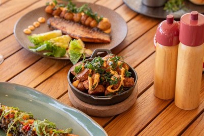 Chambre d'hôtel lumineuse avec lit double, bureau, fauteuil, grandes fenêtres et vue sur un balcon.