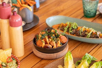 Chambre d'hôtel lumineuse avec lit double, bureau, fauteuil, grandes fenêtres et vue sur un balcon.