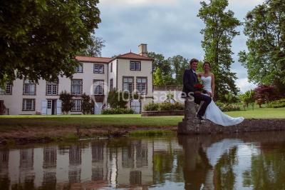 Étang naturel entouré de végétation, avec des chaises longues en arrière-plan et des pierres au premier plan.