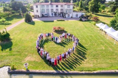 Étang naturel entouré de végétation, avec des chaises longues en arrière-plan et des pierres au premier plan.