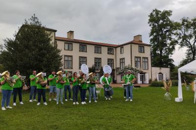 Étang naturel entouré de végétation, avec des chaises longues en arrière-plan et des pierres au premier plan.