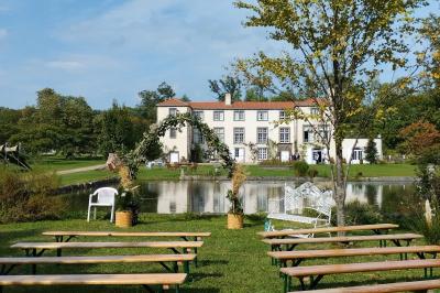 Étang naturel entouré de végétation, avec des chaises longues en arrière-plan et des pierres au premier plan.