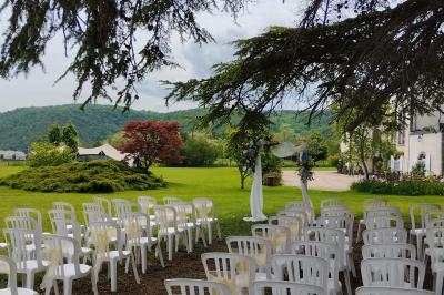 Étang naturel entouré de végétation, avec des chaises longues en arrière-plan et des pierres au premier plan.