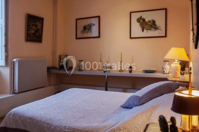 Étang naturel entouré de végétation, avec des chaises longues en arrière-plan et des pierres au premier plan.