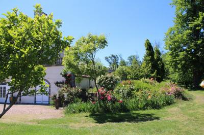 Un groupe de personnes pose devant un tracteur rouge et une machine agricole, devant un grand bâtiment ancien.