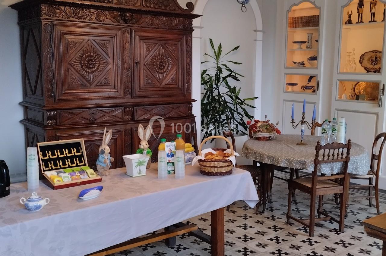Salle à manger avec buffet ancien, table dressée pour un petit-déjeuner et sol en carreaux de ciment.