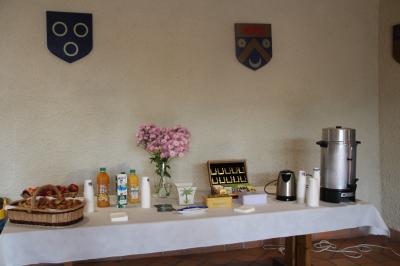 Un groupe de personnes pose devant un tracteur rouge et une machine agricole, devant un grand bâtiment ancien.