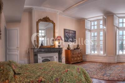 Un groupe de personnes pose devant un tracteur rouge et une machine agricole, devant un grand bâtiment ancien.