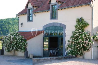 Un groupe de personnes pose devant un tracteur rouge et une machine agricole, devant un grand bâtiment ancien.