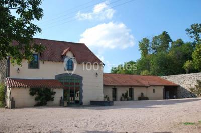Un groupe de personnes pose devant un tracteur rouge et une machine agricole, devant un grand bâtiment ancien.