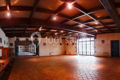 Un groupe de personnes pose devant un tracteur rouge et une machine agricole, devant un grand bâtiment ancien.