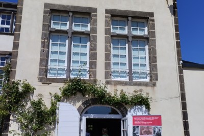 Un espace extérieur avec une table dressée près d'un étang, des arbres et un groupe de personnes au loin.