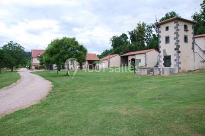 Un groupe de personnes pose devant un tracteur rouge et une machine agricole, devant un grand bâtiment ancien.