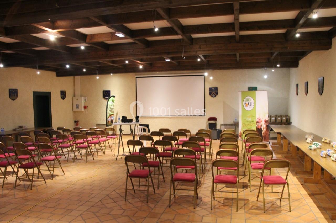 Salle de conférence avec rangées de chaises vides, écran de projection et éclairage au plafond en bois.