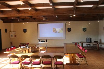 Un groupe de personnes pose devant un tracteur rouge et une machine agricole, devant un grand bâtiment ancien.