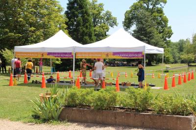 Un groupe de personnes pose devant un tracteur rouge et une machine agricole, devant un grand bâtiment ancien.