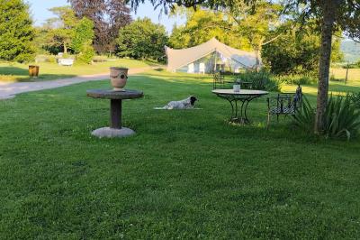 Un groupe de personnes pose devant un tracteur rouge et une machine agricole, devant un grand bâtiment ancien.