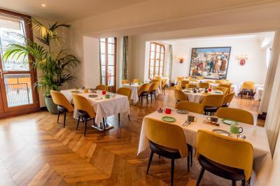 Une femme de dos sur une terrasse, face au Vieux-Port de Marseille, avec une table dressée pour le petit-déjeuner.