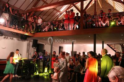 Table de réception décorée avec nappes blanches, serviettes vertes pliées, chaises ornées de nœuds verts et centre de table…