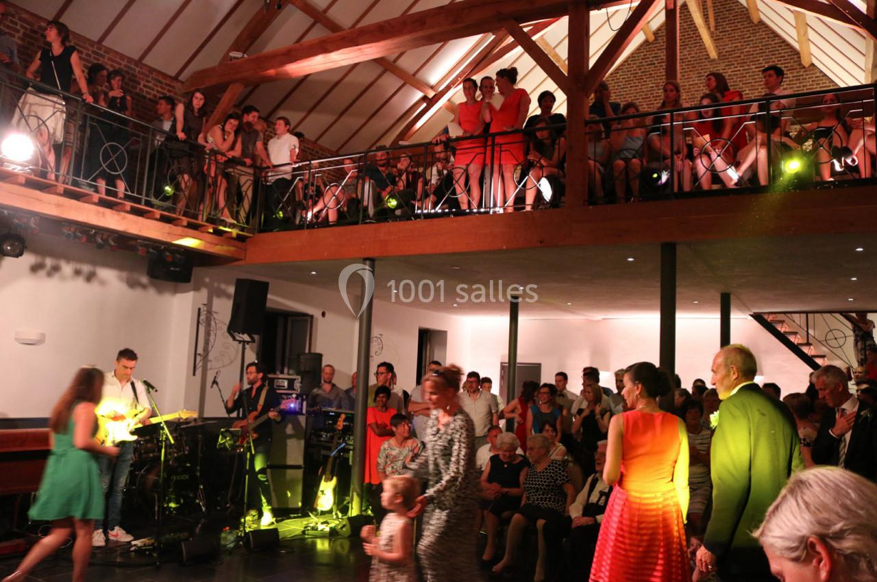 Groupe de musique jouant dans une salle avec mezzanine, entouré d'invités debout et assis lors d'un événement festif.