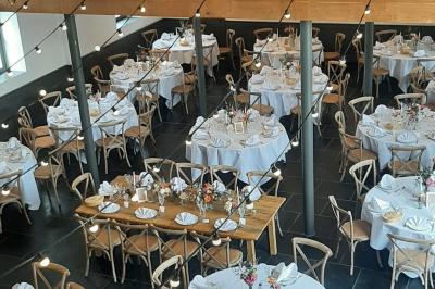 Table de réception décorée avec nappes blanches, serviettes vertes pliées, chaises ornées de nœuds verts et centre de table…