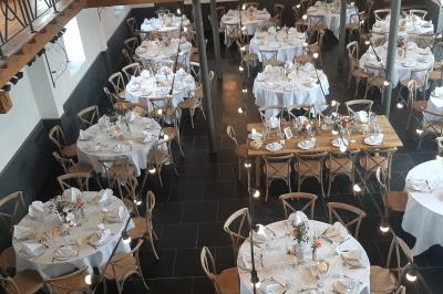 Table de réception décorée avec nappes blanches, serviettes vertes pliées, chaises ornées de nœuds verts et centre de table…