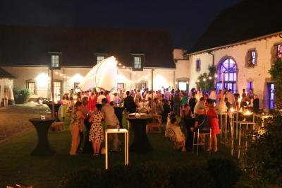 Table de réception décorée avec nappes blanches, serviettes vertes pliées, chaises ornées de nœuds verts et centre de table…