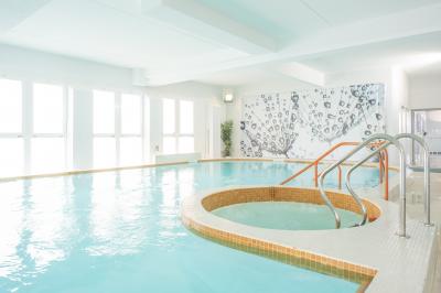 Femme allongée recevant un massage sous une douche d'eau, dans un cadre lumineux et relaxant.