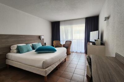 Quatre chevaux blancs galopent sur une plage au bord de l'eau, sous un ciel de coucher de soleil.