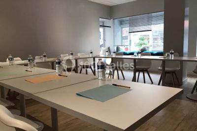 Salle avec un présentoir, des cartons empilés, une table haute décorée et un fond rouge marqué ’50 ans’.