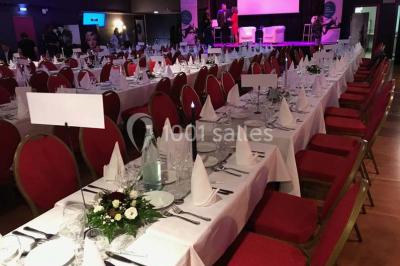 Salle avec un présentoir, des cartons empilés, une table haute décorée et un fond rouge marqué ’50 ans’.