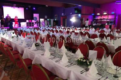 Salle avec un présentoir, des cartons empilés, une table haute décorée et un fond rouge marqué ’50 ans’.