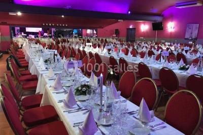 Salle avec un présentoir, des cartons empilés, une table haute décorée et un fond rouge marqué ’50 ans’.