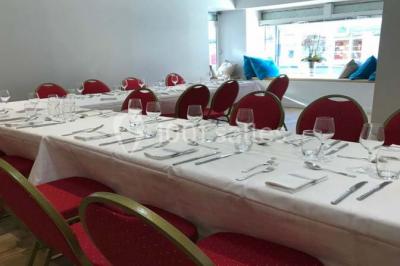 Salle avec un présentoir, des cartons empilés, une table haute décorée et un fond rouge marqué ’50 ans’.