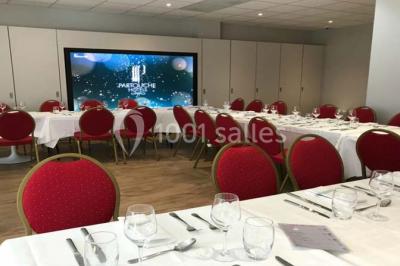 Salle avec un présentoir, des cartons empilés, une table haute décorée et un fond rouge marqué ’50 ans’.
