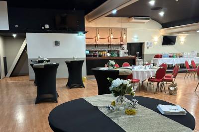 Salle avec un présentoir, des cartons empilés, une table haute décorée et un fond rouge marqué ’50 ans’.